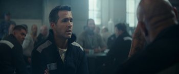 Movie still from “Red Notice” (2021), directed by Rawson Marshall Thurber – A man in a black jacket is in front of a group of people; Close Up shot, Over the shoulder angle