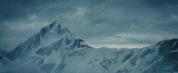 Movie still from “Red Notice” (2021), directed by Rawson Marshall Thurber – A view of a snowy mountain with a cloudy sky above it; Extreme Wide shot, Low angle