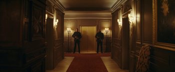 Movie still from “Red Notice” (2021), directed by Rawson Marshall Thurber – Two security guards standing in front of an entrance to a building; Wide shot, Low angle