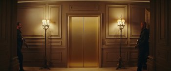 Movie still from “Red Notice” (2021), directed by Rawson Marshall Thurber – A gold elevator with two lights on either side of it; Extreme Wide shot, Low angle