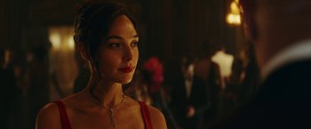 Movie still from “Red Notice” (2021), directed by Rawson Marshall Thurber – A beautiful woman in a red dress looking at the camera; Close Up shot, Over the shoulder angle