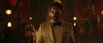 Movie still from “Red Notice” (2021), directed by Rawson Marshall Thurber – A man in a tuxedo holding a glass of champagne; Close Up shot, Over the shoulder angle