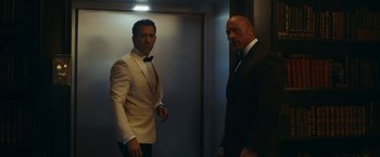 Movie still from “Red Notice” (2021), directed by Rawson Marshall Thurber – Two men in tuxedos standing next to each other in an elevator; Medium shot, Low angle