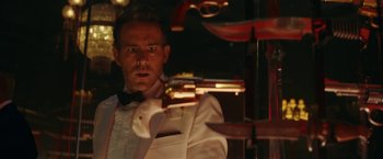 Movie still from “Red Notice” (2021), directed by Rawson Marshall Thurber – A man in a tuxedo holding a gun in front of a mirror; Close Up shot, Over the shoulder angle