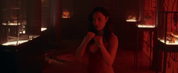 Movie still from “Red Notice” (2021), directed by Rawson Marshall Thurber – A beautiful young woman in a red dress holding her hands up; Medium shot, Over the shoulder angle
