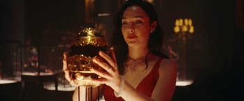 Movie still from “Red Notice” (2021), directed by Rawson Marshall Thurber – A woman in a red dress looking at a golden object; Close Up shot, Low angle