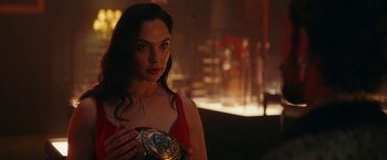 Movie still from “Red Notice” (2021), directed by Rawson Marshall Thurber – A woman in a red dress holding a medal in her hand; Close Up shot, Over the shoulder angle