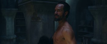 Movie still from “Red Notice” (2021), directed by Rawson Marshall Thurber – A man with a beard is standing in the dark; Close Up shot, Over the shoulder angle