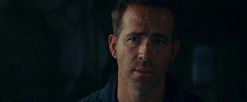 Movie still from “Red Notice” (2021), directed by Rawson Marshall Thurber – A person wearing a blue shirt; Close Up shot, Over the shoulder angle