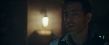 Movie still from “Red Notice” (2021), directed by Rawson Marshall Thurber – A person in a room lit by a lamp; Close Up shot, Over the shoulder angle