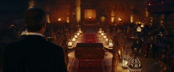 Movie still from “Red Notice” (2021), directed by Rawson Marshall Thurber – A group of people standing in a room with lit candles; Extreme Wide shot, High angle