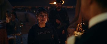 Movie still from “Red Notice” (2021), directed by Rawson Marshall Thurber – A woman in a police uniform and a man in a black uniform; Medium shot, Over the shoulder angle
