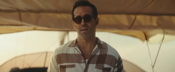 Movie still from “Red Notice” (2021), directed by Rawson Marshall Thurber – A person wearing a shirt and sunglasses; Close Up shot, Over the shoulder angle