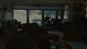 Movie still from “Reptile” (2023), directed by Grant Singer – A living room filled with couches and chairs and tables; Extreme Wide shot, High angle