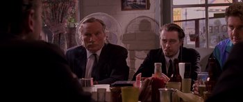 Movie still from “Reservoir Dogs” (1992), directed by Quentin Tarantino – Two men sitting at a dinner table in suits and ties; Medium shot, Over the shoulder angle