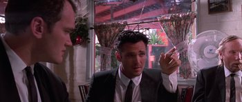 Movie still from “Reservoir Dogs” (1992), directed by Quentin Tarantino – A man sitting at a table with a cell phone in front of him; Medium shot, Low angle