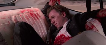 Movie still from “Reservoir Dogs” (1992), directed by Quentin Tarantino – A man in a car with blood on his face; Medium shot, High angle