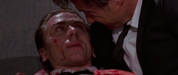 Movie still from “Reservoir Dogs” (1992), directed by Quentin Tarantino – A man with a bloody face and a man with blood on his face; Close Up shot, Low angle