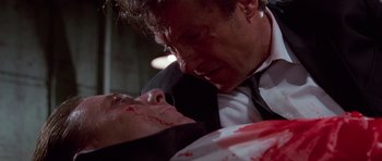 Movie still from “Reservoir Dogs” (1992), directed by Quentin Tarantino – A man in a black suit and a woman in a white dress with blood all over them; Close Up shot, Low angle