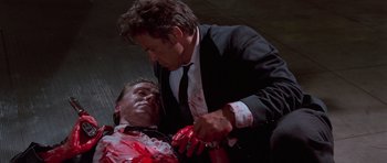 Movie still from “Reservoir Dogs” (1992), directed by Quentin Tarantino – A man in a black suit and a man in a white shirt and red tie; Medium shot, Low angle
