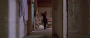 Movie still from “Reservoir Dogs” (1992), directed by Quentin Tarantino – A man in a suit standing next to a bathroom sink; Wide shot, Low angle