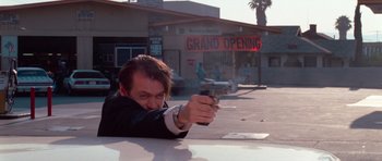 Movie still from “Reservoir Dogs” (1992), directed by Quentin Tarantino – A man holding a gun pointed at the ground; Medium shot, Low angle