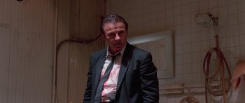 Movie still from “Reservoir Dogs” (1992), directed by Quentin Tarantino – A man in a suit and tie standing in a room; Medium shot, Low angle