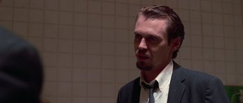 Movie still from “Reservoir Dogs” (1992), directed by Quentin Tarantino – A person wearing a suit and tie; Close Up shot, Over the shoulder angle