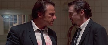 Movie still from “Reservoir Dogs” (1992), directed by Quentin Tarantino – Two men in suits talking to each other in a bathroom; Close Up shot, Low angle