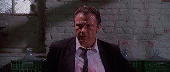 Movie still from “Reservoir Dogs” (1992), directed by Quentin Tarantino – A person wearing a suit and tie; Medium shot, Low angle