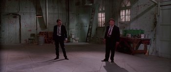 Movie still from “Reservoir Dogs” (1992), directed by Quentin Tarantino – A couple of men standing next to each other in a room; Wide shot, High angle