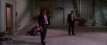 Movie still from “Reservoir Dogs” (1992), directed by Quentin Tarantino – Two men in suits and ties standing in an empty room; Wide shot, Low angle