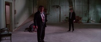 Movie still from “Reservoir Dogs” (1992), directed by Quentin Tarantino – A man in a suit and tie standing in an empty room; Wide shot, Low angle