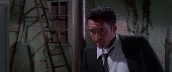 Movie still from “Reservoir Dogs” (1992), directed by Quentin Tarantino – A man wearing a suit and tie next to a metal pole; Close Up shot, Low angle