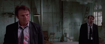 Movie still from “Reservoir Dogs” (1992), directed by Quentin Tarantino – A man standing in a room next to a toilet; Close Up shot, Over the shoulder angle