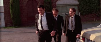 Movie still from “Reservoir Dogs” (1992), directed by Quentin Tarantino – A group of men in suits walking down a street; Medium shot, Low angle