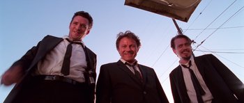 Movie still from “Reservoir Dogs” (1992), directed by Quentin Tarantino – A group of men standing next to each other in suits; Medium shot, Low angle