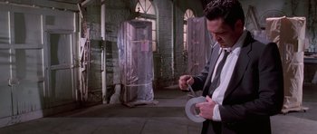 Movie still from “Reservoir Dogs” (1992), directed by Quentin Tarantino – A man holding a pair of scissors in his hands; Medium shot, Low angle