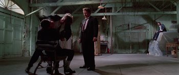 Movie still from “Reservoir Dogs” (1992), directed by Quentin Tarantino – A man in a suit and tie standing next to another man in a suit; Wide shot, Low angle