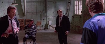 Movie still from “Reservoir Dogs” (1992), directed by Quentin Tarantino – A man in a suit and tie standing next to another man in a suit; Wide shot, High angle