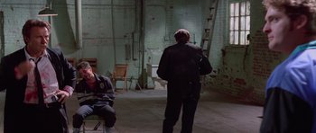 Movie still from “Reservoir Dogs” (1992), directed by Quentin Tarantino – A man standing in an empty room with a ladder; Wide shot, High angle