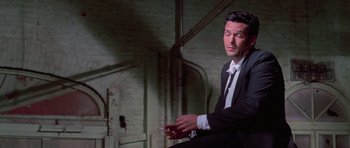 Movie still from “Reservoir Dogs” (1992), directed by Quentin Tarantino – A man in a suit and tie holding a cell phone; Medium shot, Low angle