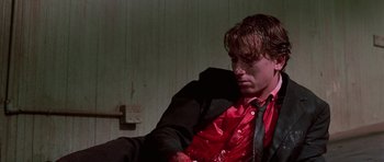 Movie still from “Reservoir Dogs” (1992), directed by Quentin Tarantino – A man in a red shirt and black tie; Medium shot, Low angle