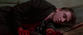 Movie still from “Reservoir Dogs” (1992), directed by Quentin Tarantino – A man in a black suit is laying on the ground; Close Up shot, High angle