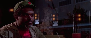 Movie still from “Reservoir Dogs” (1992), directed by Quentin Tarantino – A man in a red shirt wearing a green hat and holding a cigarette; Close Up shot, Low angle