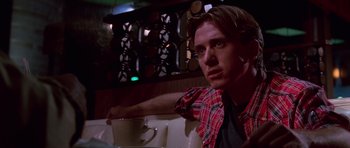 Movie still from “Reservoir Dogs” (1992), directed by Quentin Tarantino – A man sitting at a table with a cup of coffee in front of him; Close Up shot, Over the shoulder angle