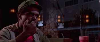 Movie still from “Reservoir Dogs” (1992), directed by Quentin Tarantino – A man sitting at a table with a cup in front of him; Close Up shot, Low angle