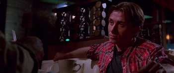 Movie still from “Reservoir Dogs” (1992), directed by Quentin Tarantino – A man sitting in front of a wine rack; Close Up shot, Low angle