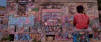 Movie still from “Reservoir Dogs” (1992), directed by Quentin Tarantino – A wall covered in graffiti and a person standing in front of it; Wide shot, Low angle