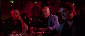 Movie still from “Reservoir Dogs” (1992), directed by Quentin Tarantino – A man sitting at a table with a drink in front of him; Medium shot, Over the shoulder angle